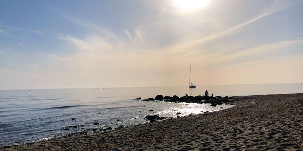 A picture of a sunny and sandy beach. In the background, the Mediterranean Sea with a ship sailing.